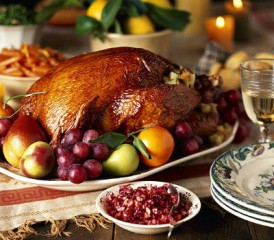 Cooked turkey and fruit on a plate with other side dishes on a table Cooked turkey and fruit on a plate with other side dishes on a table